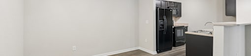 A kitchen area with a black refrigerator, microwave, and oven.