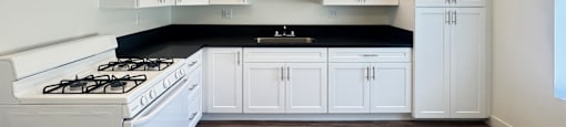 A kitchen with white cabinets and a black countertop.