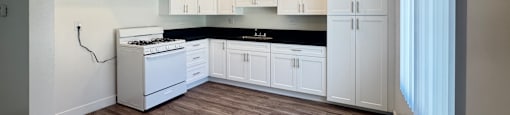 A kitchen with white cabinets and a black countertop.