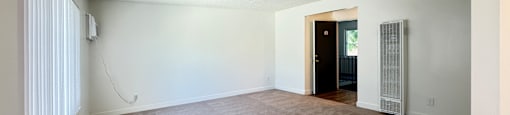A room with a carpeted floor and a door on the right side.