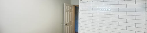 A white tiled bathroom with a black countertop and a white sink.
