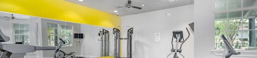 A gym with treadmills, elliptical machines, and a fan.