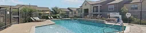 A swimming pool surrounded by a fence and a few lounge chairs.