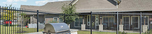 A house with a stone pillar and a mailbox in front of a black fence.