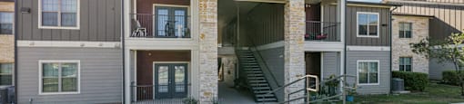 A modern two-story apartment building with a stone facade and a central entrance.
