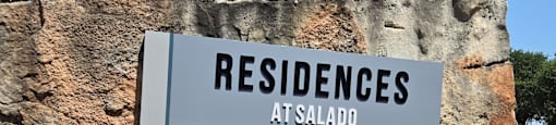 A sign for Residences at Salado is mounted on a stone wall.