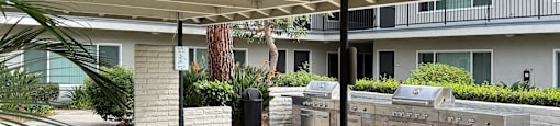 A patio area with a grill and a building in the background.