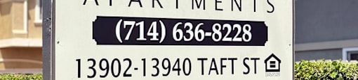 A sign for Orange Tree Apartments with a phone number and address.