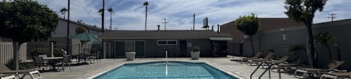 A large outdoor swimming pool with lounge chairs and a building in the background.