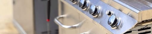 A stainless steel grill with a lid and a side burner.