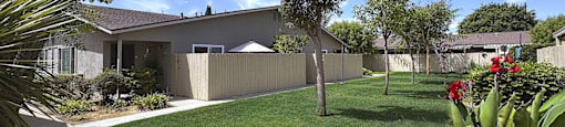 A house with a white fence and a green lawn.