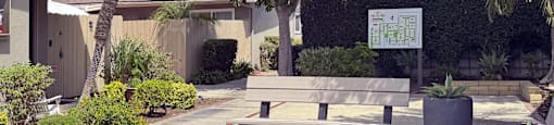 A sunny day at a park with a bench and a tree.