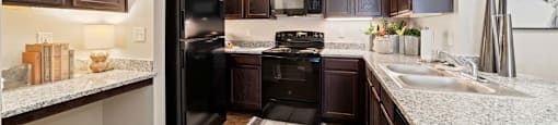 A kitchen with dark brown cabinets and black appliances. at Residences at the Landing, Texas, 78028