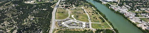 A river flows through a city with a bridge crossing over it. at Residences at the Landing, Kerrville
