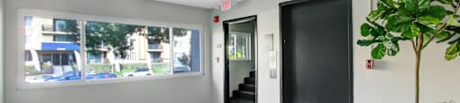 A room with a black door and a window with a view of the street.