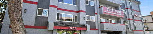 A building with a red and white striped facade and a tree in front.