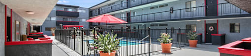 A patio with a pool and a red umbrella.