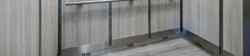 A row of stainless steel hand dryers in a public restroom.