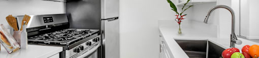A modern kitchen with a stainless steel refrigerator, oven, and white cabinets.