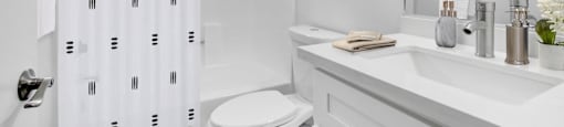 A white bathroom with a toilet, sink, and shower curtain.
