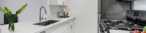 A modern kitchen with white cabinets and stainless steel appliances.