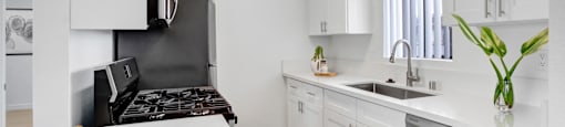 A kitchen with a white countertop and a bowl of bananas on it.
