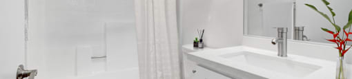 A white bathroom with a toilet, sink, and shower.