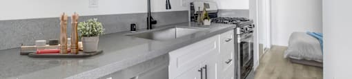 A kitchen with white cabinets and a grey counter top.