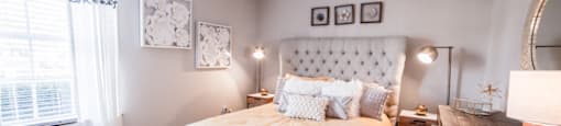 Bedroom with a window and neutral colored walls at Chelsea Village Apartments