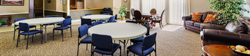 Clubhouse at Fairington Apartments in Anderson with tables and chairs and a couch.