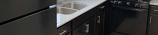 Spacious Kitchen with Espresso Cabinets and Black Appliances at Carriage House West.
