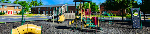 Playground at Carriage House Evansville, featuring swings and play structures.