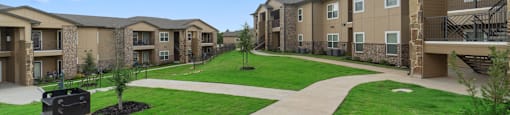 a view of an apartment complex with a green lawn and sidewalk