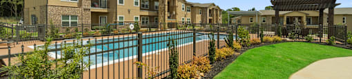 a swimming pool with a fence in front of an apartment building