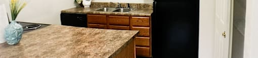 a kitchen with black appliances and wooden cabinets and a marble counter top