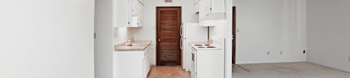 A kitchen area with white appliances and a tiled floor.