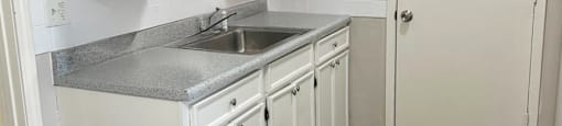 A kitchen with white cabinets and a wooden floor.