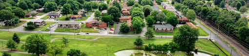 A flooded park with a pond in the middle and houses in the background.