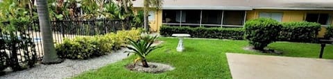 lush courtyard with green grass, patio, and birdbath