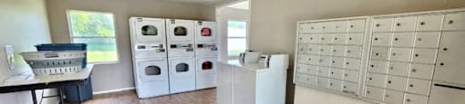mailboxes and laundry center with washers, dryers, and folding table