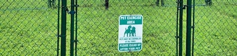 large fenced bark park with agility course