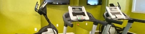 fitness center with cardio equipment and TV