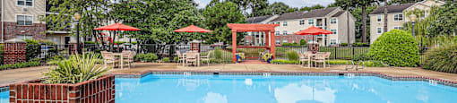 A pool surrounded by a red fence and trees.