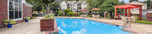 A pool surrounded by a red brick border with a red gazebo in the background.