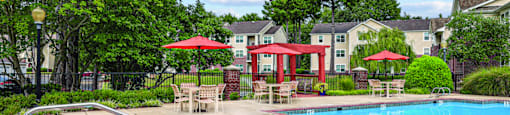 A pool with a slide and a red umbrella.
