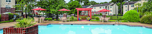 A pool surrounded by a red fence and trees.