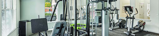 A gym with a variety of equipment including a treadmill, weights, and a television.
