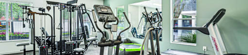 A gym with a variety of equipment including treadmills, weights, and exercise machines.
