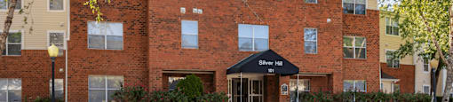 Parking Lot and Sidewalk in Front of Leasing Office Entrance with Awning and Shrubs