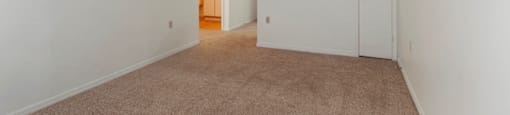 Open Floor Plan with Carpeted Living Room and Kitchen with Breakfast Bar White Cabinets and White Appliances Next to Front Door